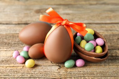 Ahşap masada renkli şekerlemeli lezzetli çikolata yumurtaları, yakın plan. Mutlu Paskalyalar