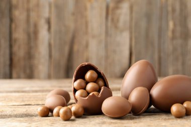 Mutlu Paskalyalar. Ahşap masada şekerli çikolatalı yumurtalar, yakın plan. Metin için boşluk