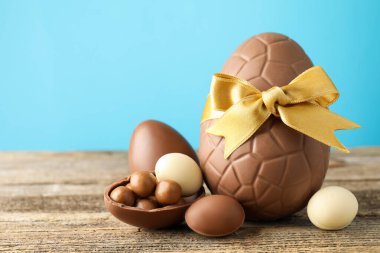 Mutlu Paskalyalar. Ahşap masa üzerinde çikolatalı yumurtalar açık mavi arka planda, yakın plan. Metin için boşluk