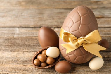 Mutlu Paskalyalar. Ahşap masada şekerli çikolatalı yumurtalar, yakın plan. Metin için boşluk