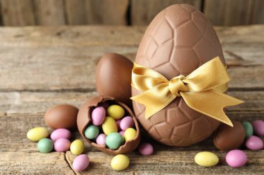 Mutlu Paskalyalar. Ahşap masada renkli şekerlemeli lezzetli çikolata yumurtaları, yakın plan. Metin için boşluk