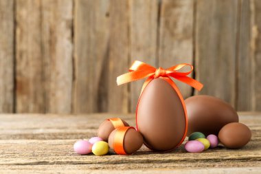 Mutlu Paskalyalar. Ahşap masada renkli şekerlemeli lezzetli çikolata yumurtaları, yakın plan. Metin için boşluk