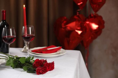 İçinde şarap kadehleri, yanan mumlar ve kapalı mekanlarda kırmızı güller olan güzel bir masa. Metin için boşluk