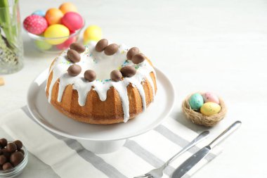 Çikolatalı lezzetli Paskalya pastası ve beyaz masaya boyanmış yumurtalar, yakın plan.
