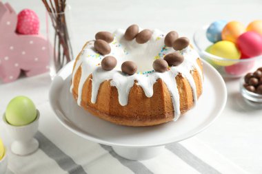Çikolatalı lezzetli Paskalya pastası ve beyaz masaya boyanmış yumurtalar, yakın plan.