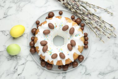 Çikolatalı lezzetli Paskalya pastası, beyaz mermer masada boyanmış yumurtalar ve söğüt dalları, düz uzanmış.