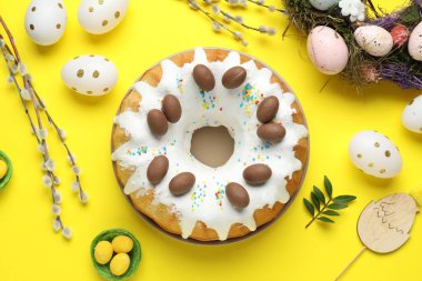 Lezzetli Paskalya pastası, boyanmış yumurtalar ve sarı arka planda söğüt dalları, düz uzanmış