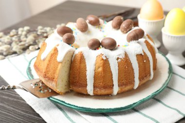 Lezzetli Paskalya pastası. Kapalı masa üzerinde boyalı yumurtalar, sunucu ve söğüt dalları. Yakın plan.