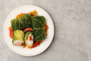 Gri arka planda sebzelerle servis edilen lahana dolması, üst manzara. Metin için boşluk