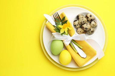 Paskalya kutlaması. Sarı arka planda nergis çiçekleri ve bıldırcın yumurtaları olan şenlik masası, üst manzara. Metin için boşluk