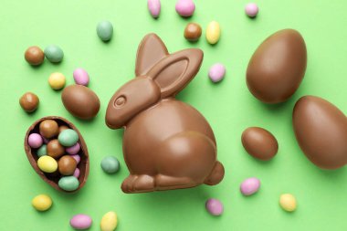 Çikolatalı Paskalya tavşanı ve açık yeşil arka planda yumurtalar.