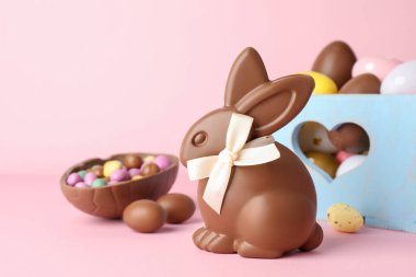 Çikolatalı Paskalya tavşanı ve pembe arka planda yumurtalar, yakın plan.