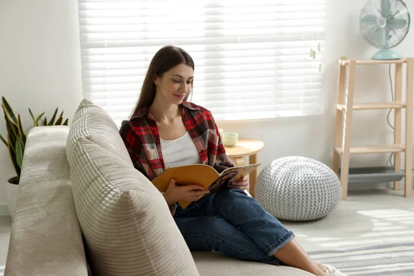 Dergisi olan kadın evdeki kanepede dinleniyor.