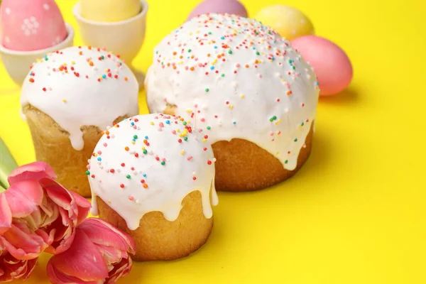 Lezzetli Paskalya pastaları, yumurta ve laleler sarı arka planda, yakın plan.