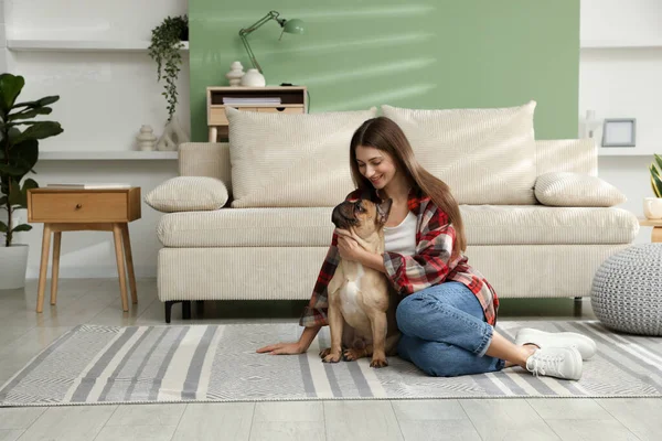 Evdeki kanepenin yanında sevimli köpeği olan bir kadın.