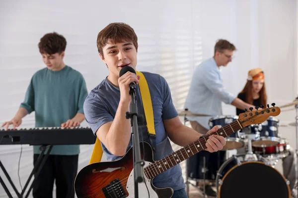 Genç müzik grubu içeride performanslarını prova ediyor.