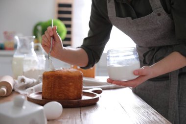 Geleneksel Paskalya pastasını mutfakta jöleli dekore eden genç bir kadın.