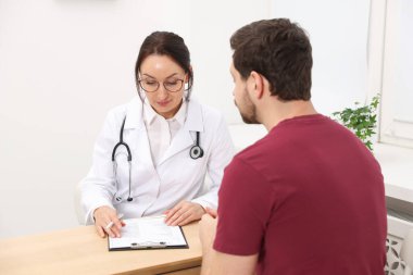 Klinikteki ahşap masada pano danışmanı olan bir doktor.