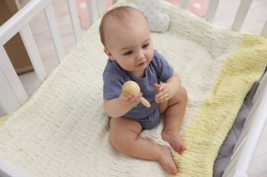 Evinde beşiğinde ahşap çıngıraklı şirin bir bebek.