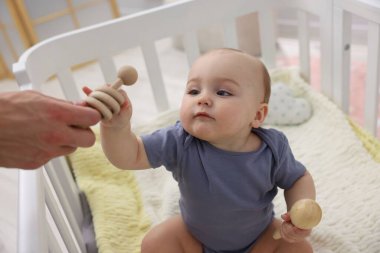 Babası evdeki beşiğinde sevimli küçük bebeğiyle oynuyor, yakın plan.