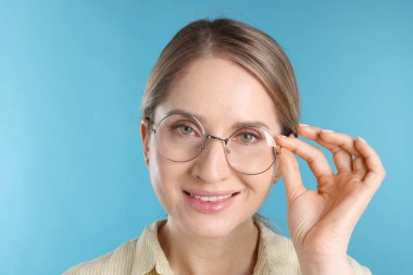 Açık mavi arka planda gözlüklü kadın