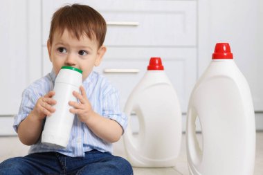 Evde çocuk güvenliği. Mutfakta temizlik malzemesi olan küçük bir çocuk.