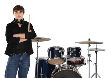 Kulaklıkları, bagetleri ve davulları beyaz arka planda olan genç bir çocuk.