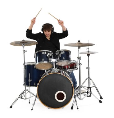 Kulaklıklı, bagetleriyle davul çalmayı öğrenen genç bir çocuk.