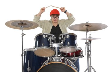 Gözlüklü ve bagetli şapkalı genç çocuk beyaz arka planda davul çalmayı öğreniyor.