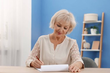 Ahşap masada son dilek ve vasiyetnameyi imzalayan kıdemli kadın.