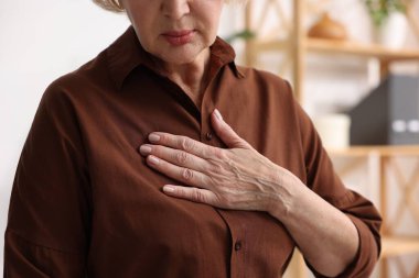 Kalp krizi geçirdi. Üst düzey kadın göğüs ağrısı çekiyor. Kapalı bir yerde, yakın plan.