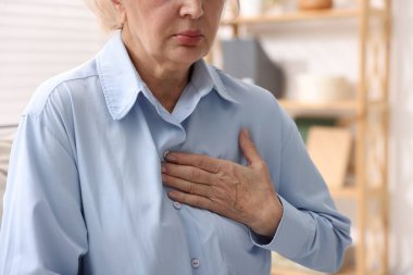 Kalp krizi geçirdi. Üst düzey kadın göğüs ağrısı çekiyor. Kapalı bir yerde, yakın plan.