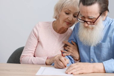 Ahşap masada son arzuları ve vasiyetnameleri imzalayan yaşlı çift.