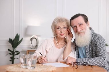 Ahşap masada son arzuları ve vasiyetnameleri imzalayan yaşlı çift.