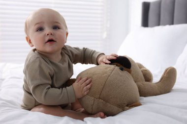 Evde yatağında oyuncak ayıyla sevimli bir bebek.