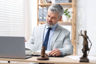 Takım elbiseli noter masada kitap okuyor.