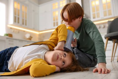 İki kardeş evde megafonla oynaşıyor.