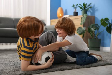 İki kardeş evde futbol topuyla oynaşıyor.