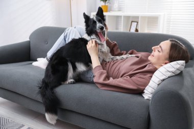 Evdeki kanepede sevimli köpeğiyle gülümseyen kadın.