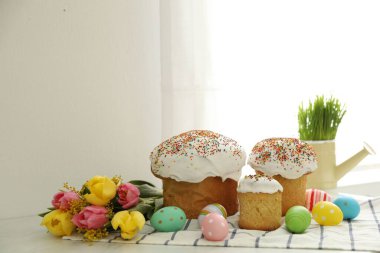 Geleneksel Paskalya pastaları, çiçekler ve boyanmış yumurtalar masada.