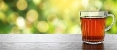 Dışarıdaki ahşap masada cam bardakta taze demlenmiş çay. Metin için alanı olan pankart tasarımı