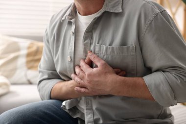 Kalp krizi geçirdi. Kapalı alanda göğüs ağrısı çeken adam, yakın plan.