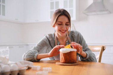 Genç bir kadın geleneksel paskalya pastasını mutfakta süslüyor.