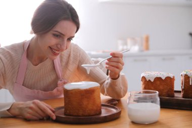Genç bir kadın geleneksel paskalya pastasını mutfakta jöleli dekore ediyor. Metin için boşluk