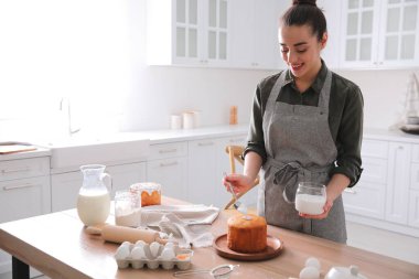Genç bir kadın geleneksel paskalya pastasını mutfakta jöleli dekore ediyor. Metin için boşluk