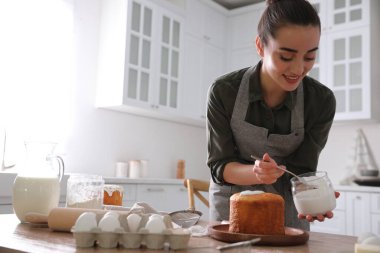 Genç bir kadın geleneksel paskalya pastasını mutfakta jöleli dekore ediyor. Metin için boşluk