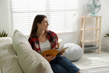 Dergisi olan kadın evdeki kanepede dinleniyor.