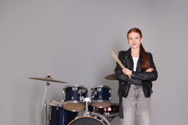 Açık gri arka planda bagetleri ve davulları olan genç bir kız. Metin için boşluk