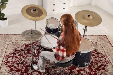 Bagetli genç kız davul çalmayı içeride, arka planda öğreniyor.