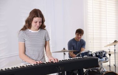 Genç müzik grubu içeride performanslarını prova ediyor.